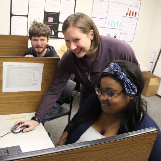 A professor assisting a student at the computer in the classroom