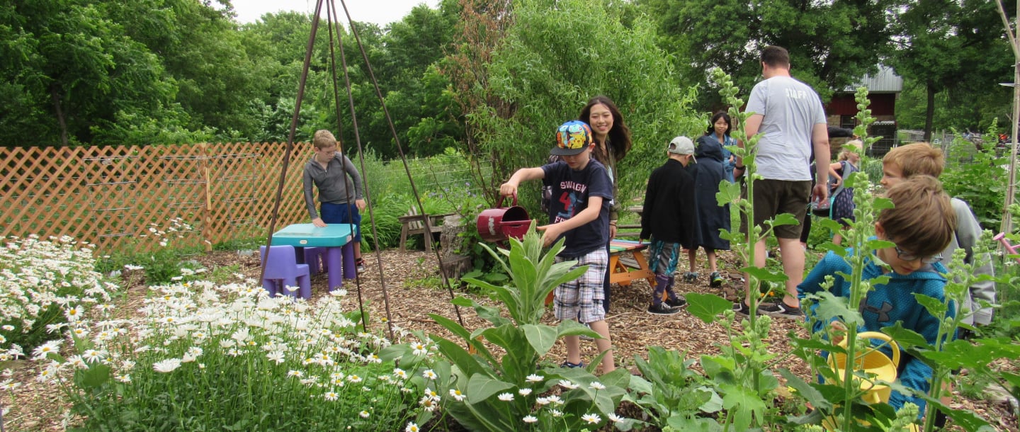 Rec N' Read kids and staff working outside in the garden watering the plants