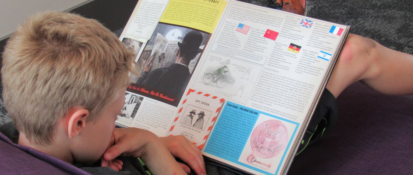 A Rec N' Read kid sitting down reading a book placed in their lap