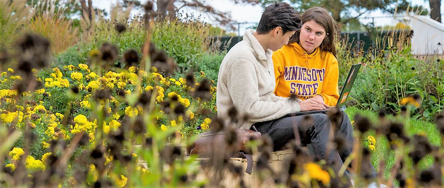 a couple of people sitting on a bench in a garden